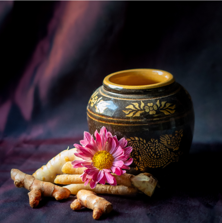 Thailändischer Topf, im Vordergrund Kurkumawurzeln und eine Blume.